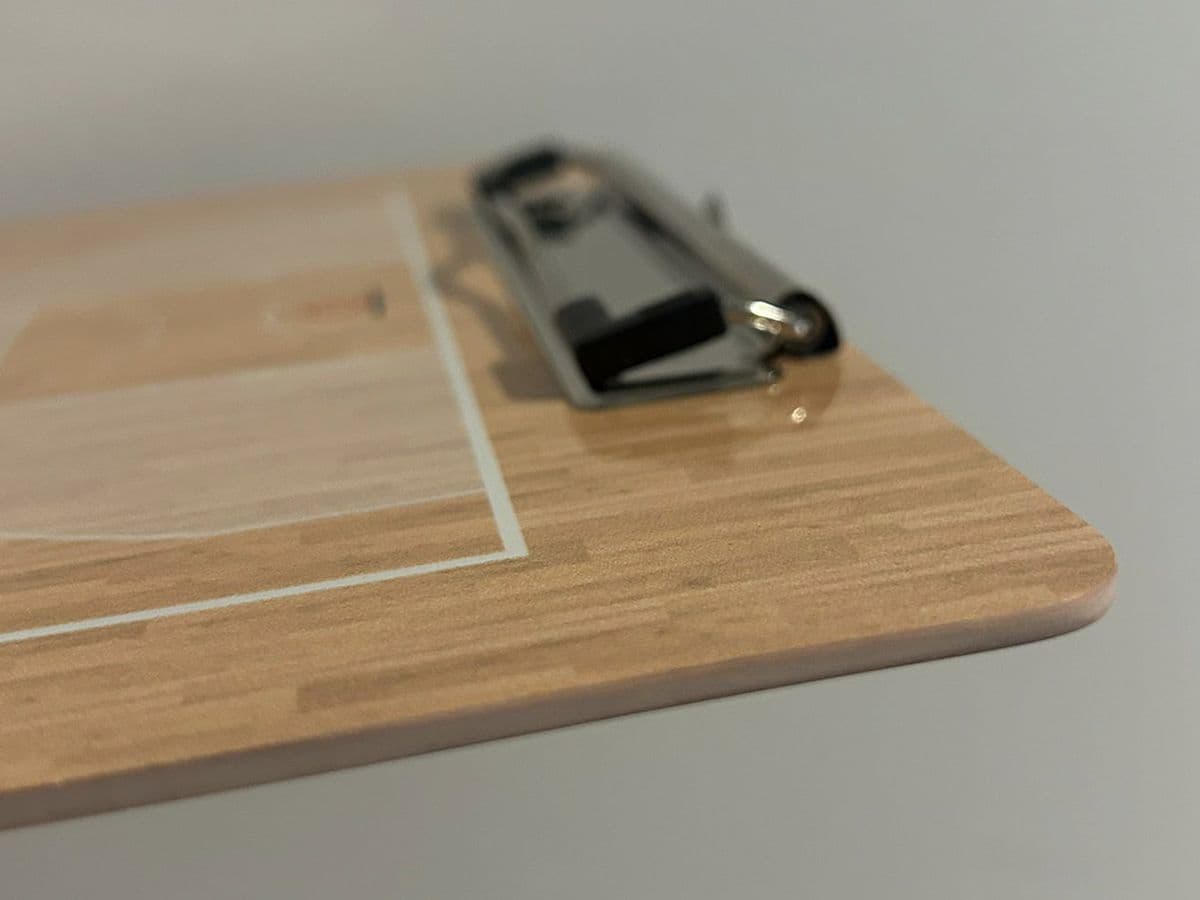 Detalhe do quadro tático em compósito (textura, cantos, porta-clip)