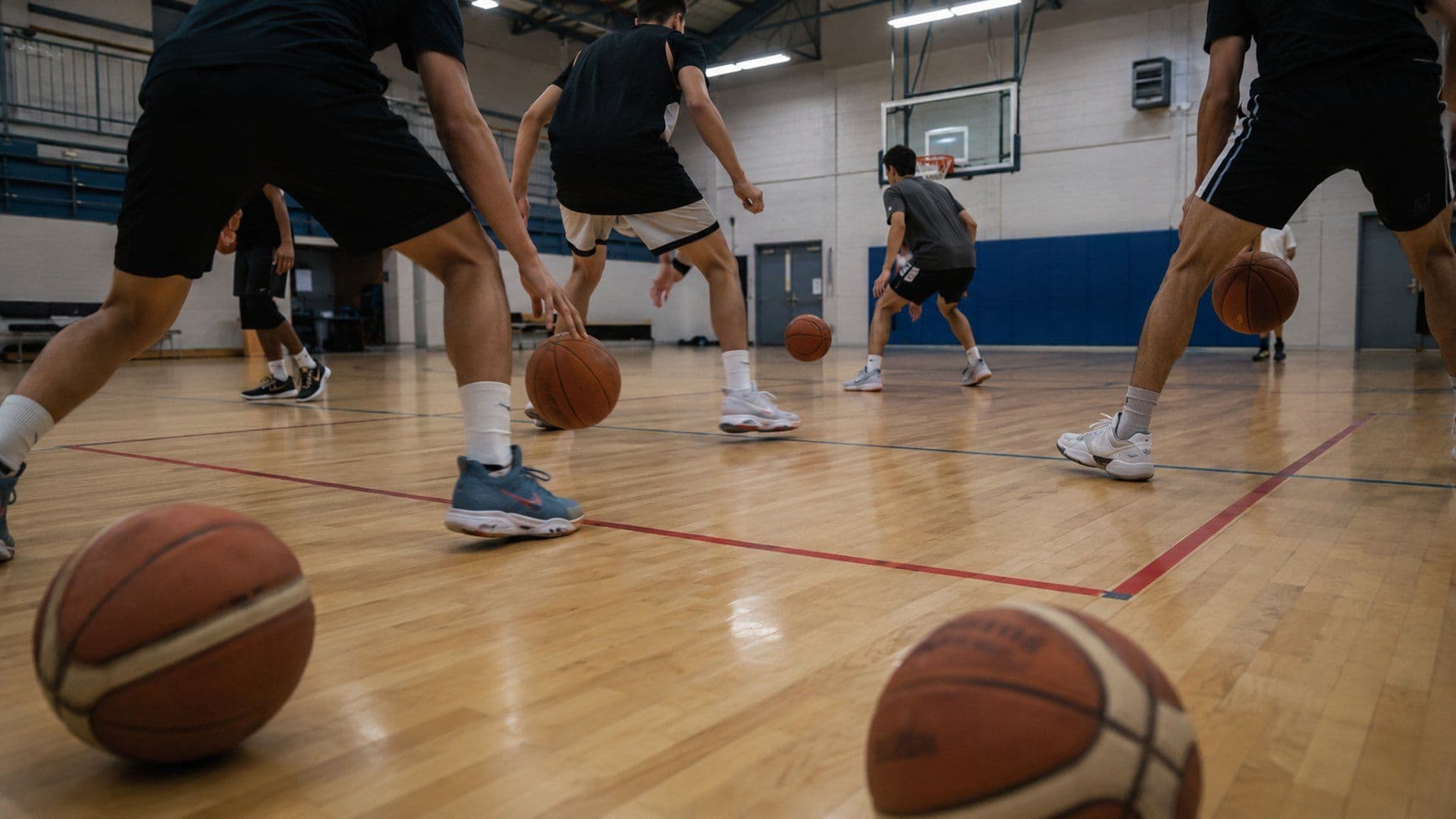 Equipa a driblar em conjunto durante o aquecimento de um treino de basquetebol